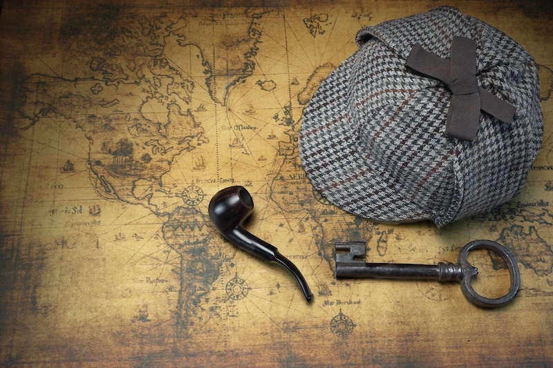 Deerstalker hat, key and pipe on a map