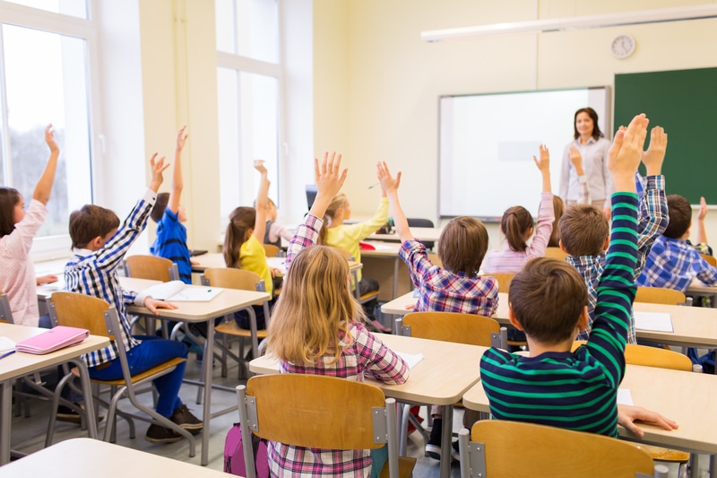 Kids with hands up in classroom